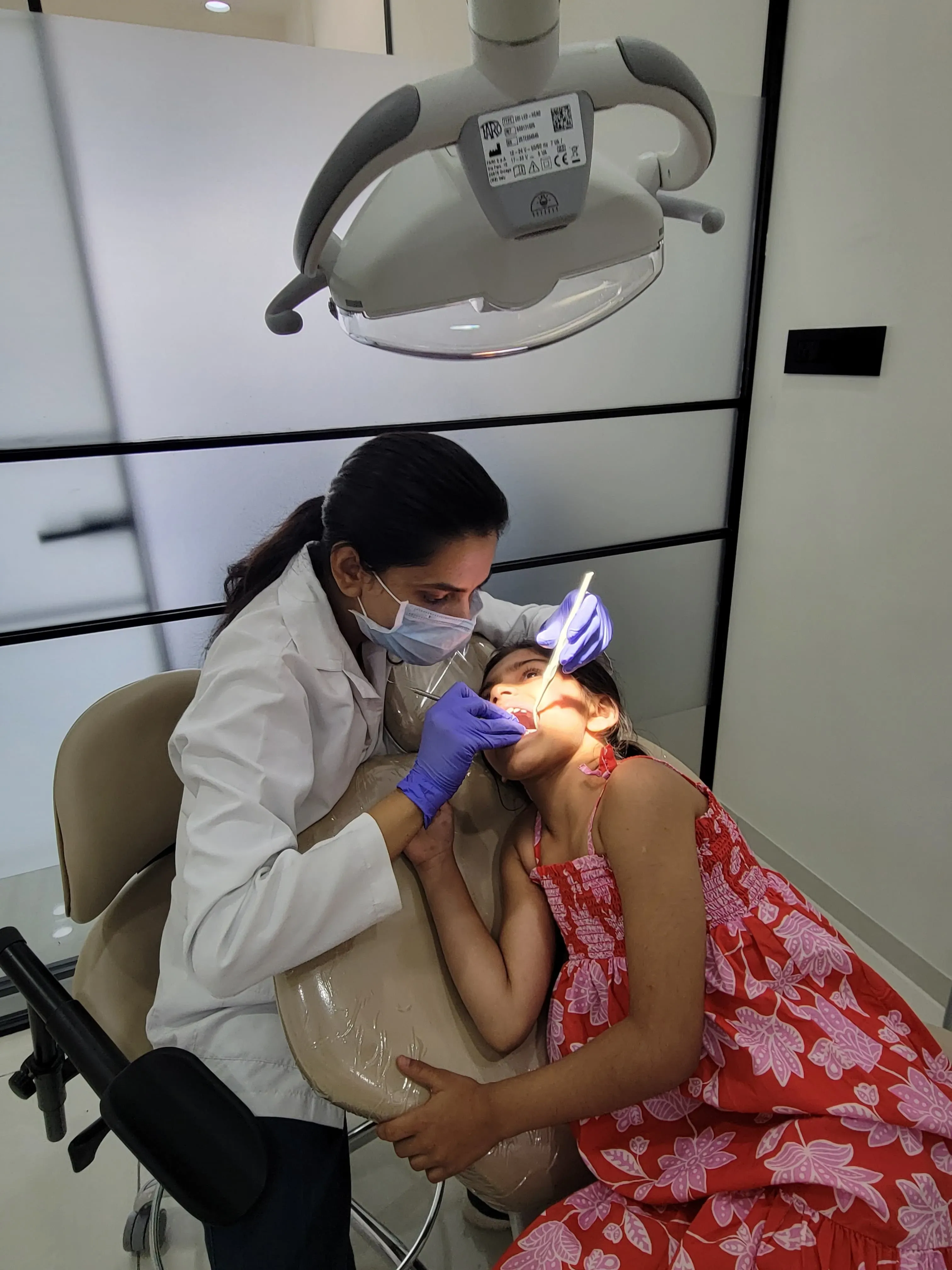 Dr. Srushti Patel performing a gentle pediatric dental check-up with mirror and light in Kudasan