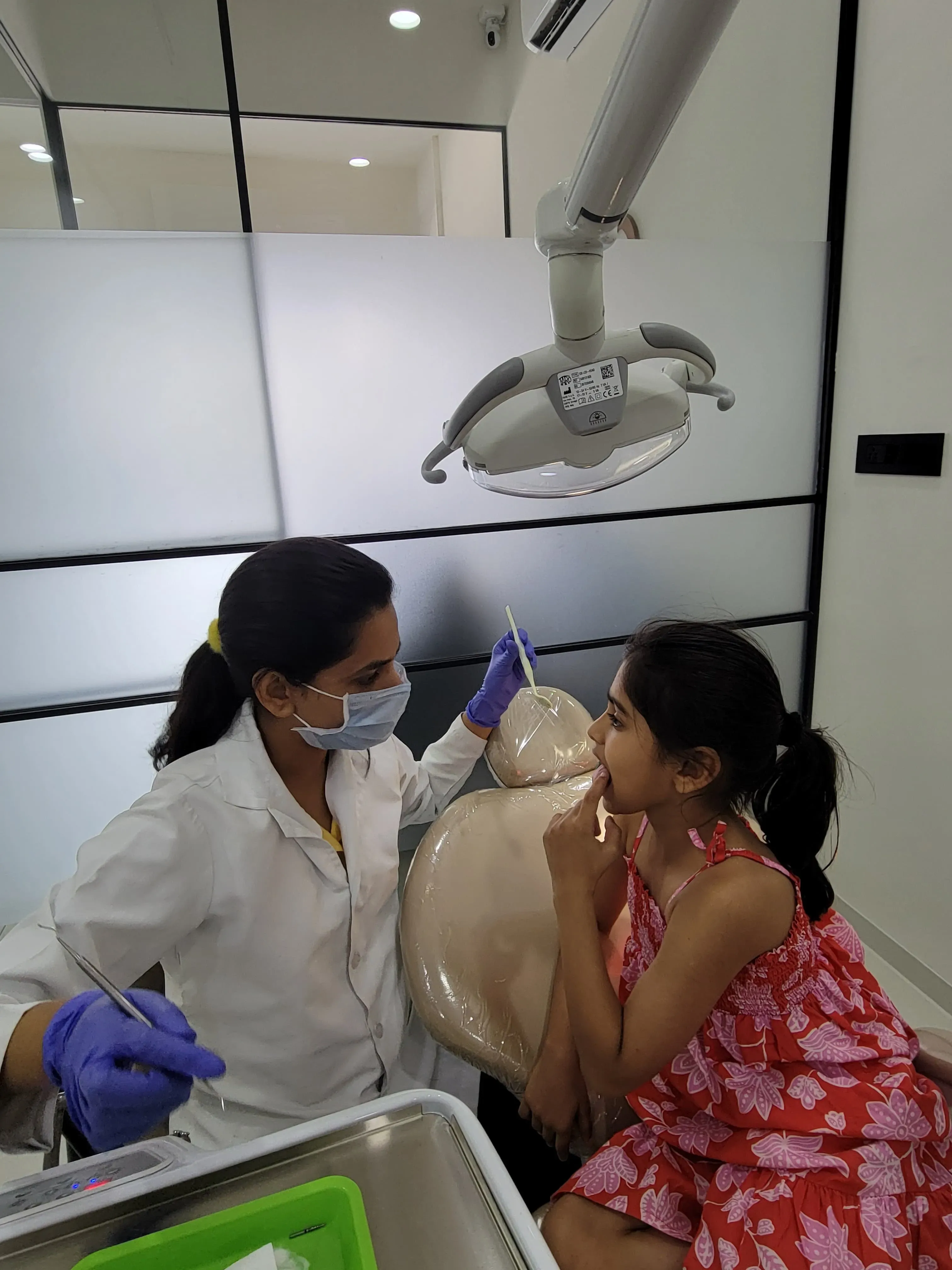 Young child smiling during a gentle pediatric dental examination by Dr. Srushti Patel in Gandhinagar